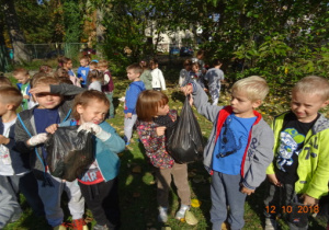 Dzieci poazują worki z zebranymi śmieciami.
